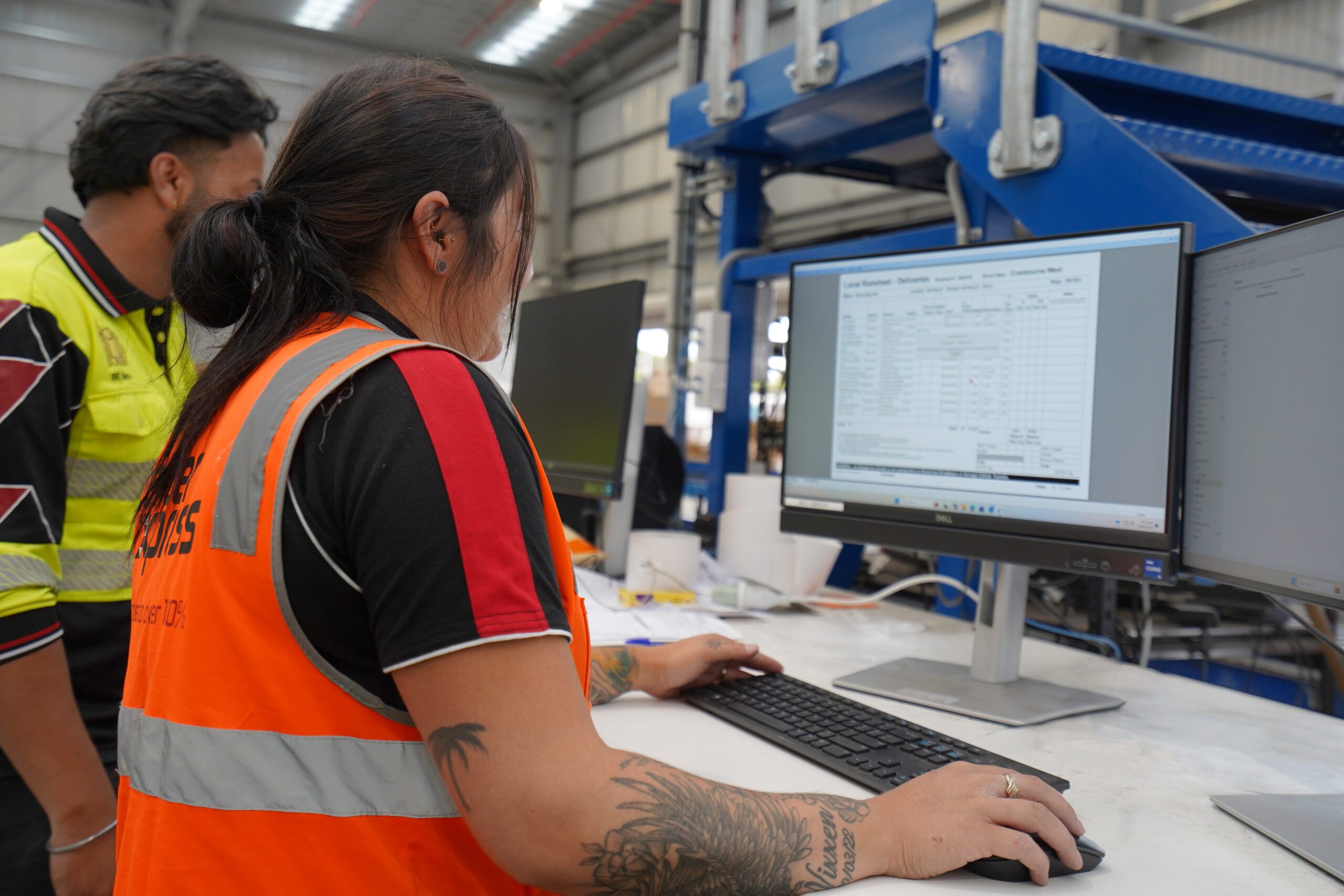 Two warehouse workers review logistics on a computer screen